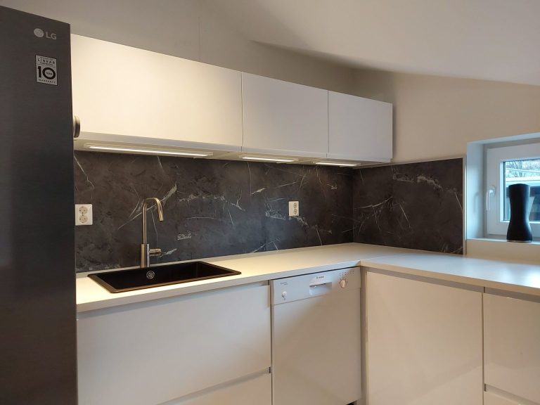 hvitt kjoekken med sort kjoeleskap og moerke vegger.