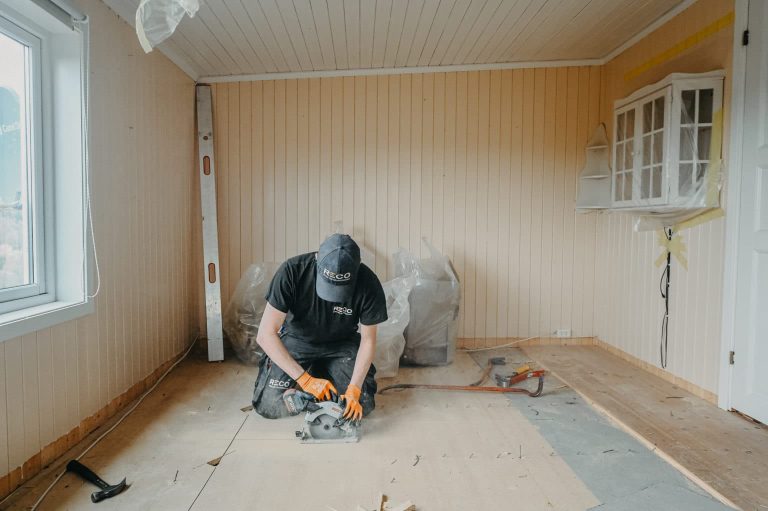 snekker sitter paa gulvet og jobber i et lyst rom.